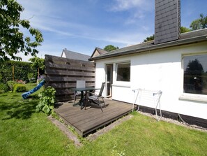 Ein Haus mit Terrasse, Rutsche und Fenster.