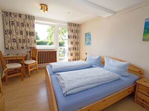 Ein Schlafzimmer mit zwei Betten, einem Holztisch, Stühlen und einer Heizung.