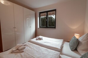 A bedroom with two beds, a wardrobe, a window, and a bedside lamp. - Villa Friede-Marie, Apt. Hannah - with a terrace and a view of the Baltic Sea (Sassnitz auf Rügen)