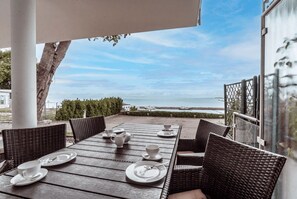 An outdoor dining area with wicker furniture and white plates, overlooking a body of water. - Villa Friede-Marie, App. Hannah - with terrace and Baltic Sea view (Sassnitz auf Rügen)