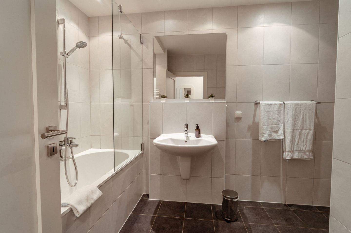 A modern bathroom with a glass-enclosed shower, a pedestal sink, and a toilet.