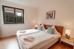 A hotel room with a double bed, two bedside tables, a window with blinds, and a framed picture on the wall. - Villa Friede-Marie, App. Hannah - with terrace and Baltic Sea view (Sassnitz auf Rügen)