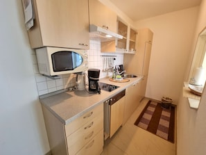 A compact kitchen with a microwave, coffee maker, and a sink. - Ferienhaus Zum Kreideblick, FeWo Muschel - Holiday home Zum Kreideblick, (Sassnitz auf Rügen)