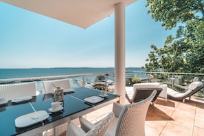 A balcony with a table set for dining, wicker chairs, and a view of the sea. - Villa Friede-Marie, App. Baltic Sea view - with fantastic sea view - Villa (Sassnitz auf Rügen)