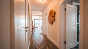 A hallway with wooden flooring, white walls, and a large wooden art piece. - Villa Friede-Marie, App. Baltic Sea view - with fantastic sea view - Villa (Sassnitz auf Rügen)