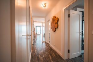 Ein Korridor mit Holzboden, weißen Wänden und einem großen Kunstwerk aus Holz.