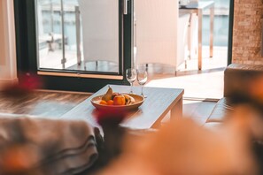 Un comedor con una mesa dispuesta para dos, un frutero y dos copas de vino.