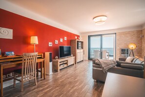 Una sala de estar moderna con televisor, muebles de madera y un balcón con vistas.