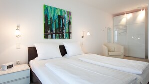 Une chambre d’hôtel comprenant un lit, une table de chevet, une lampe, des œuvres d’art et un placard avec une porte coulissante.