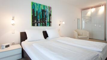 Ein Hotelzimmer mit Bett, Nachttisch, Lampe, Kunstwerk und einem Schiebetürenschrank.