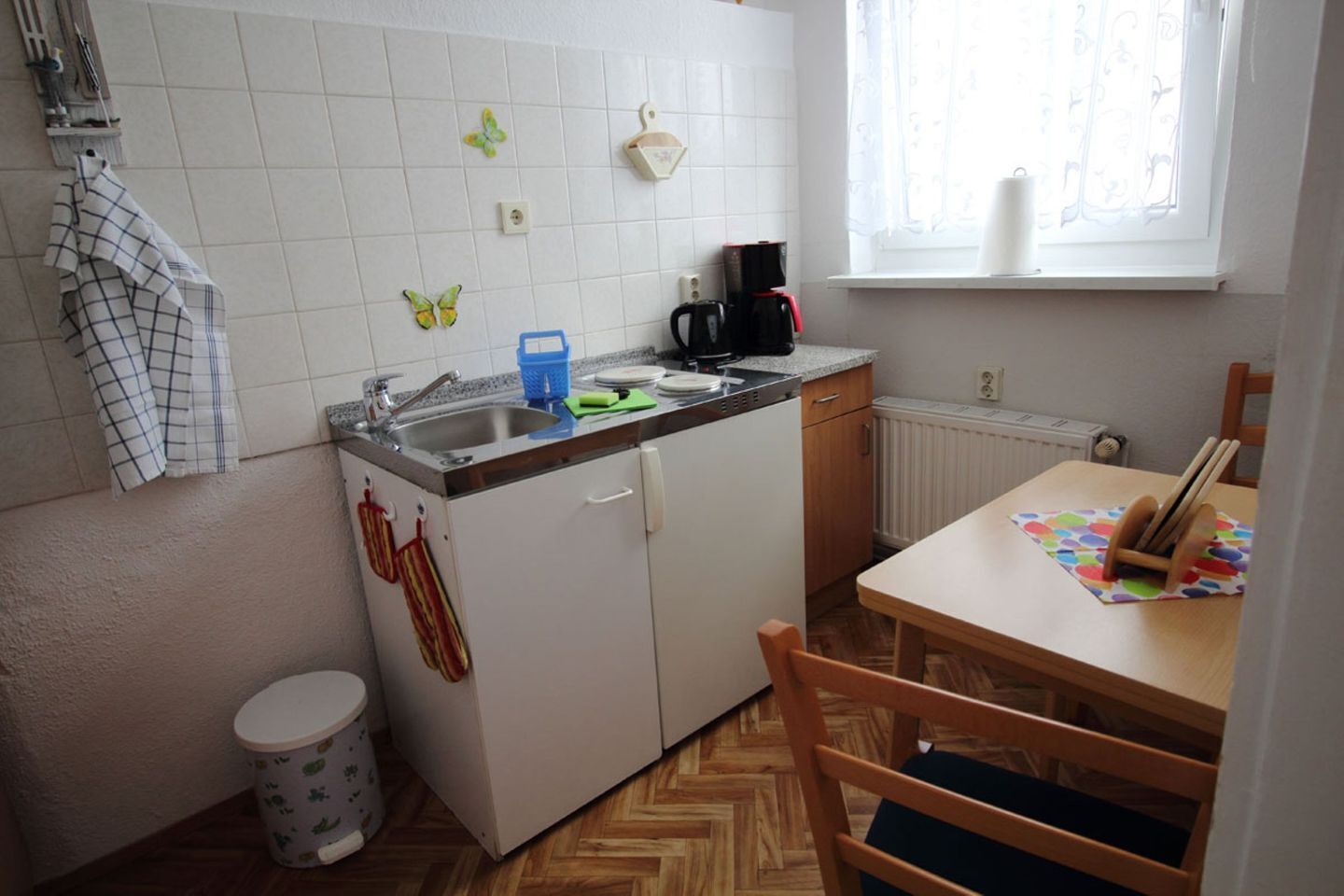 Eine kleine Küche mit Spüle, Kaffeemaschine und Fenster.