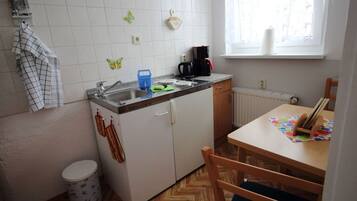 Eine kleine Küche mit Spüle, Kaffeemaschine und Fenster.