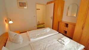 Une chambre d’hôtel avec deux lits, une armoire en bois, un miroir et un luminaire fixé au mur.