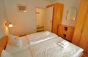 Ein Hotelzimmer mit zwei Betten, einem Holzschrank, einem Spiegel und einer Wandleuchte.