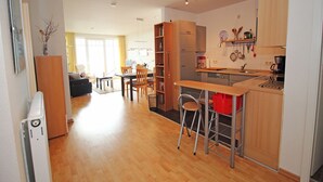 A modern kitchen with wooden cabinets, a dining area with a table and chairs, and a living room with a sofa and a coffee table. - Villa Prinz Heinrich - App.3 with balcony and Baltic Sea view - Villa Prinz Heinrich, (Sassnitz auf Rügen)