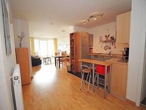 Eine moderne Küche mit Holzausstattung, ein Essbereich mit Tisch und Stühlen sowie ein Wohnzimmer mit Sofa und Couchtisch.
