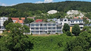 A multi-story building with balconies, surrounded by lush greenery and a mountainous backdrop. - Villa Prinz Heinrich - App.3 with balcony and Baltic Sea view - Villa Prinz Heinrich, (Sassnitz auf Rügen)