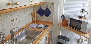 Eine kleine Küche mit Spüle, Mikrowelle und Kaffeemaschine auf einer Holzausziehtafel.