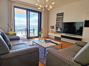 A modern living room with a large TV, comfortable seating, and a balcony with a view. - Villa Friede Marie, App. Finja - Harbor-Baltic Sea view and balcony - Villa Friede (Sassnitz auf Rügen)