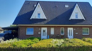 A two-story house with a dark tiled roof, brick exterior, and a picket fence in front. - Johanna vacation apartment - located on the Wieker Bodden (Wiek auf Rügen)