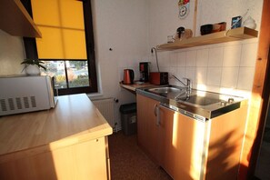 A compact kitchen with a microwave, sink, and stove. - Vacation apartment Vieth in Sassnitz on Rügen with seating area in the garden (Sassnitz auf Rügen)