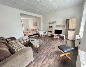 Ein modernes Wohnzimmer mit Sofa, Couchtisch, TV-Stand und Essbereich.