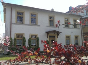 Ein mehrgeschossiges Gebäude mit einer symmetrischen Fassade, zahlreichen Fenstern und einem zentralen Eingang.