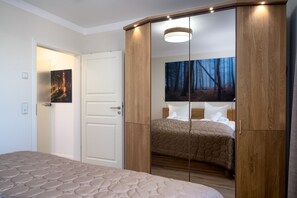 Ein Schlafzimmer mit Bett, Kleiderschrank, Tür und einem Bild an der Wand.