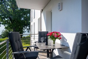 Ein Balkon mit Tisch, Stühlen, Blumen und Meerblick.