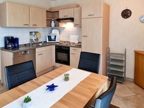 Eine kleine Küche mit Holzschränken, einer Mikrowelle, einem Toaster und einer Kaffeemaschine.