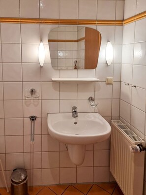 Ein Badezimmer mit einem weißen Waschbecken, einem Spiegel und zwei Wandleuchten.