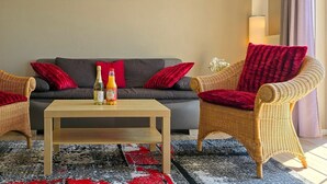 Ein Wohnzimmer mit einer Couch, zwei Sesseln, einem Couchtisch und einem Gemälde an der Wand.
