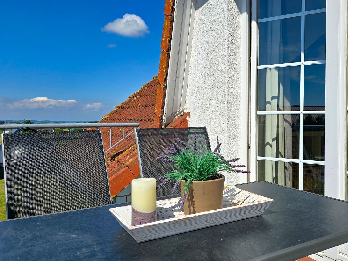 Ein Balkon mit Tisch, Kerze und einer Topfpflanze.