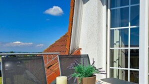Ein Balkon mit Tisch, Kerze und einer Topfpflanze.