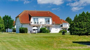 Ein geräumiges, einstöckiges Haus mit rotem Ziegeldach, weißen Wänden und einer Veranda.