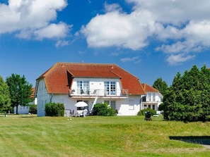 Ein geräumiges, einstöckiges Haus mit rotem Ziegeldach, weißen Wänden und einer Veranda.