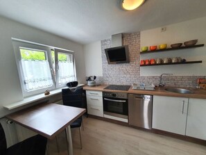 Eine moderne Küche mit Einbauofen, Geschirrspüler und Flachbildfernseher.