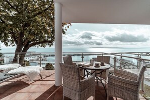 A balcony with wicker furniture, a table with books and cups, and a view of the sea and buildings. - Villa Friede-Marie, App. Svea with harbor and Baltic Sea view - Villa Friede-Marie, App. (Sassnitz auf Rügen)