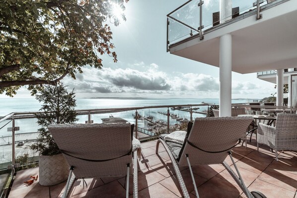 A terrace with wicker chairs and a view of the sea. - Villa Friede-Marie, App. Svea with harbor and Baltic Sea view - Villa Friede-Marie, App. (Sassnitz auf Rügen)