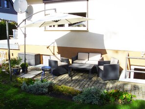 An outdoor seating area with a sofa, chairs, and a table, surrounded by potted plants and a satellite dish. - Vacation apartment on the outskirts (Sassnitz auf Rügen)
