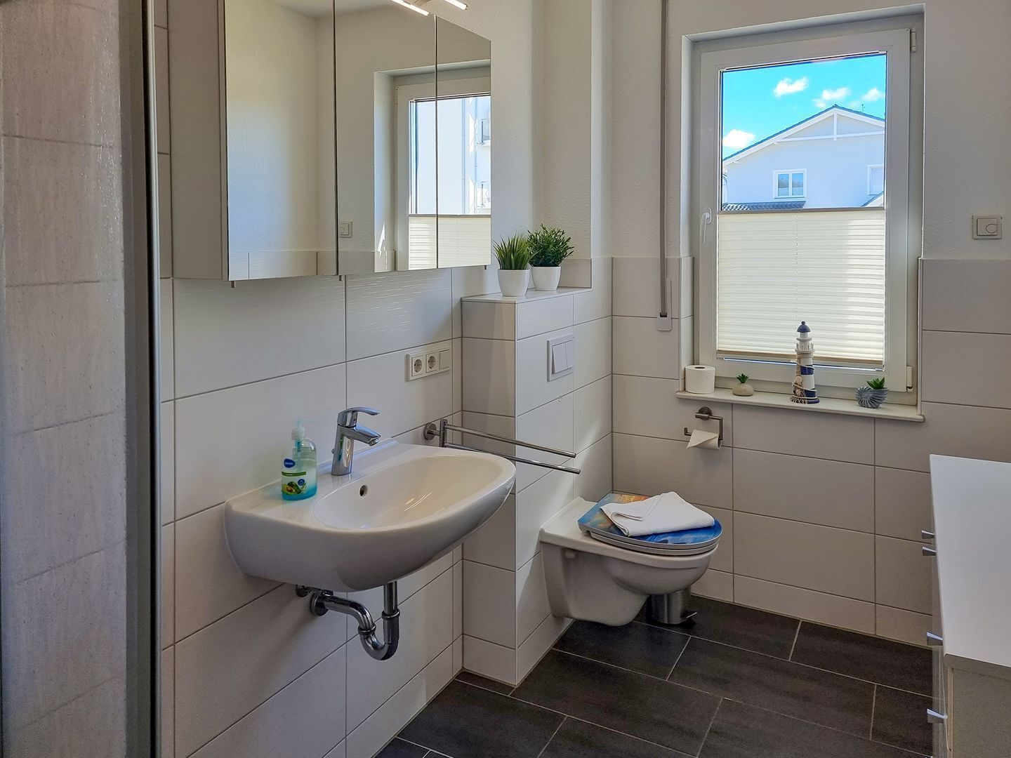 Ein modernes Badezimmer mit Waschbecken, Toilette und Fenster.