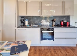 Eine moderne Küche mit Backofen, Kaffeemaschine und Wasserkocher.