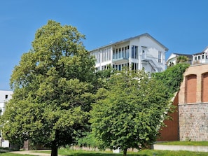 Ein mehrstöckiges Gebäude mit weißer Fassade, großen Fenstern und einer sichtbaren Treppe, die zu einer oberen Ebene führt.