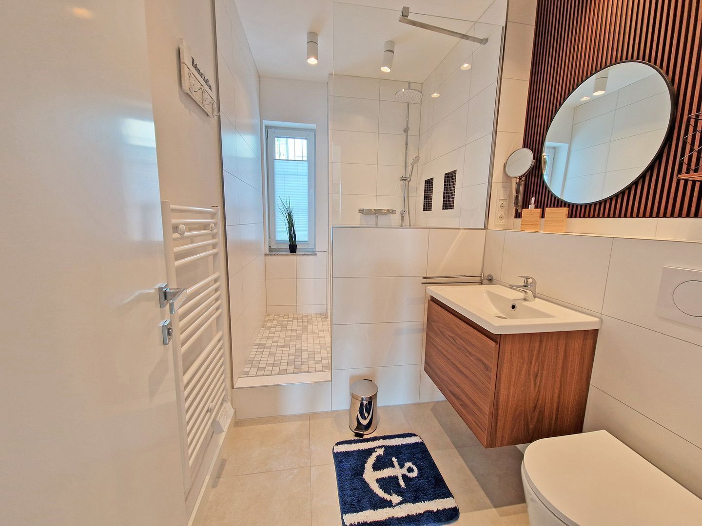 A modern bathroom with a shower, a sink, a mirror, and a towel rack.
