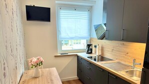 Una cocina compacta con encimera de madera, lavamanos integrado y ventana con vistas al exterior.