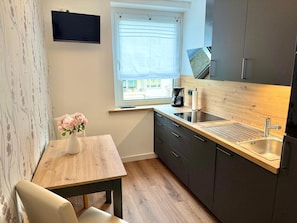 A compact kitchen with a wooden countertop, a built-in sink, and a window with a view of the outside. - Vacation apartment Little Sea Lion (Sassnitz)