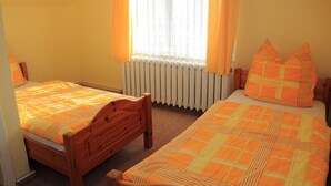 Een slaapkamer met twee bedden, een radiator en een raam met gordijnen.
