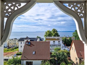 A coastal view through a decorative window frame, featuring a mix of residential buildings with varied roof styles and a clear view of the sea. - Bädervilla Emma - Holiday apartment Ostseepanorama (Sassnitz auf Rügen)