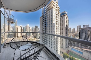 Ein Balkon mit Tisch und Stühlen, mit Blick auf eine Skyline aus Hochhäusern und einen Fluss.
