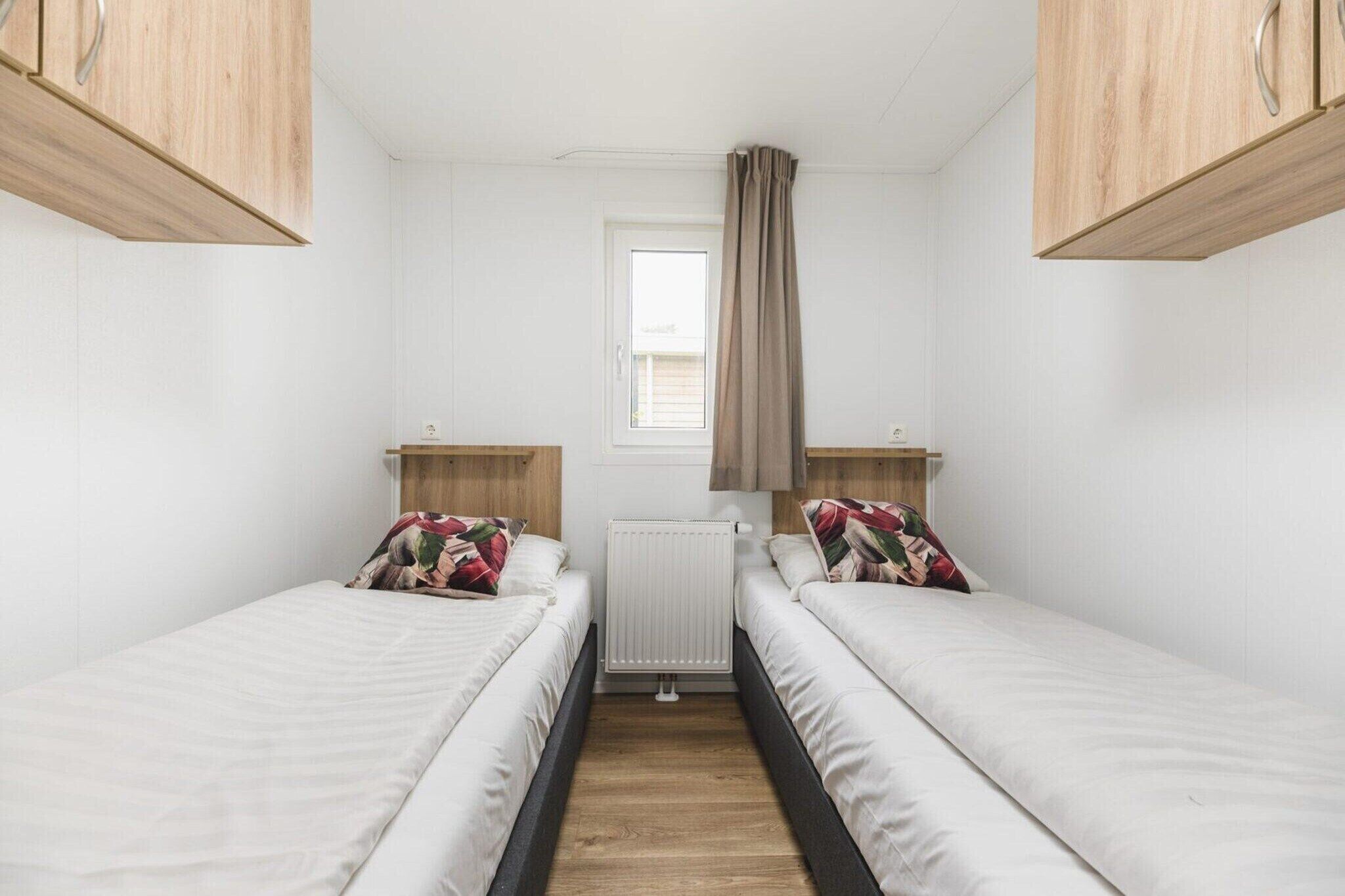 Ein kleines, sauberes Zimmer mit zwei Einzelbetten, einem Fenster mit Vorhängen und Holzschränken.
